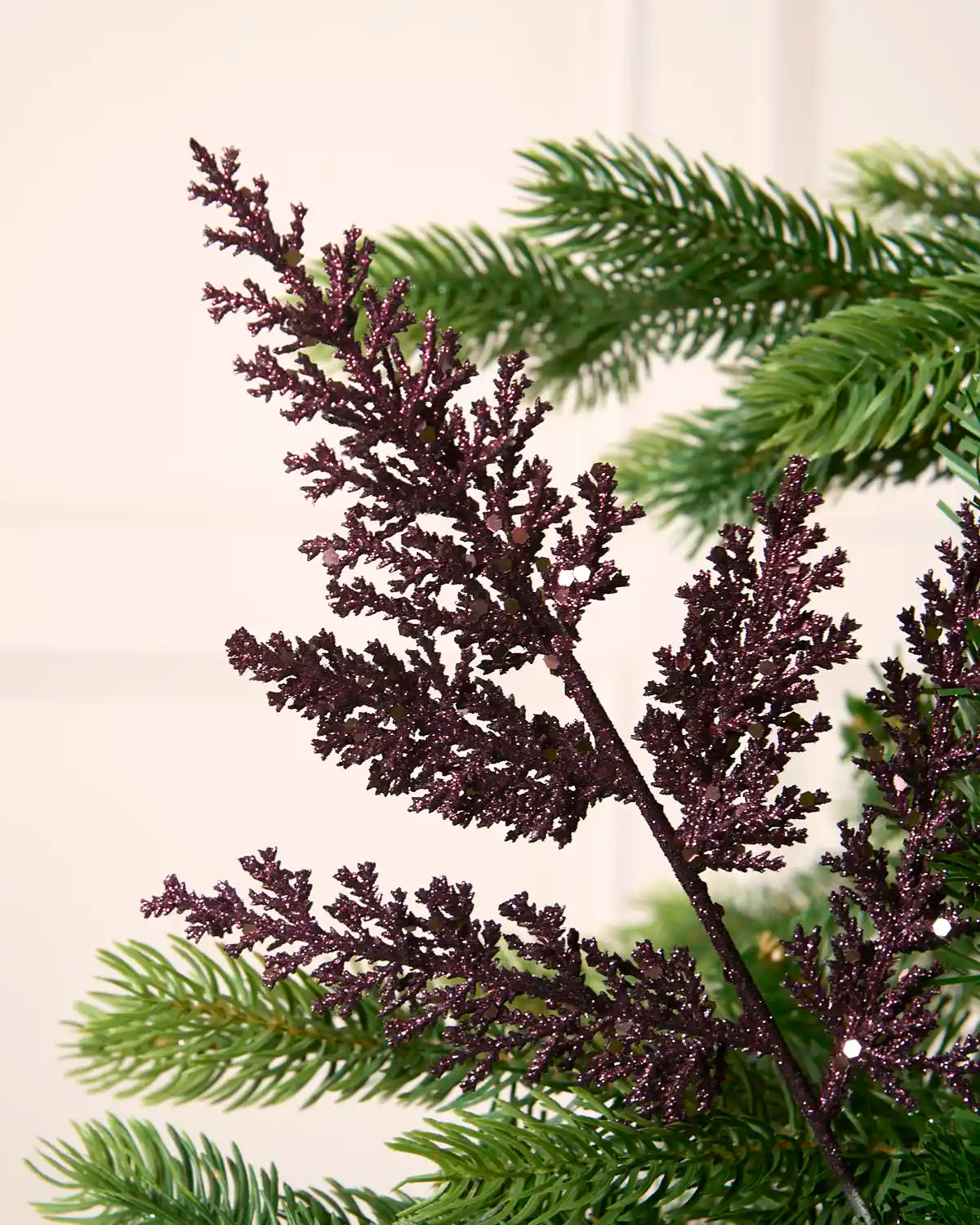 Close-up of a purple glitter leaf pick showing textured foliage and sparkling sequin detail.