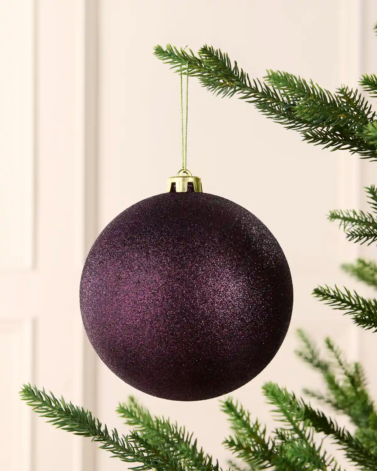 Purple 15 cm oversized shatterproof bauble with a glitter finish, gold cap and hanging string displayed on a Christmas tree.