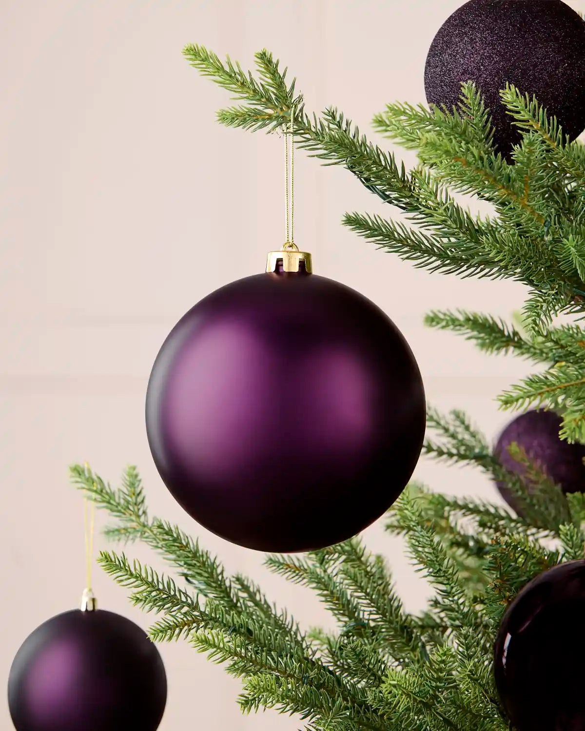 Oversized 15 cm purple matt shatterproof bauble displayed on a Christmas tree with coordinating purple baubles.