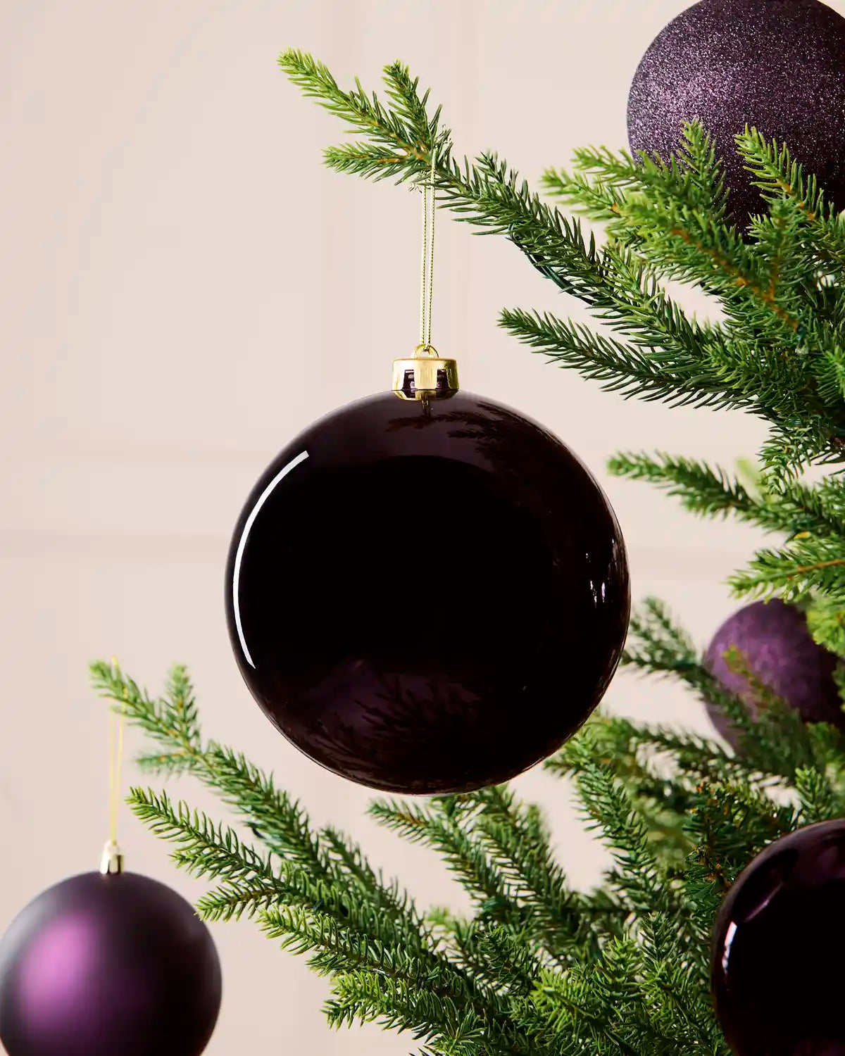 Oversized 15 cm purple shiny shatterproof bauble displayed on a Christmas tree with coordinating purple baubles.