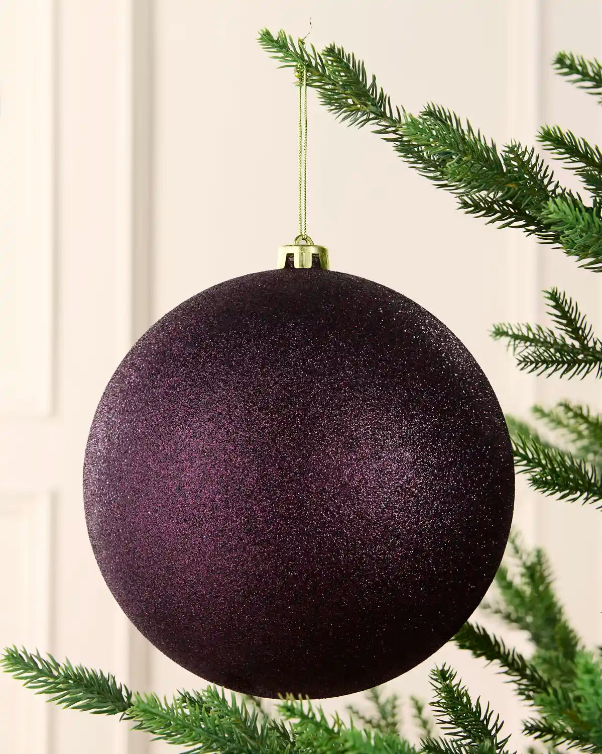 Purple 20 cm oversized shatterproof bauble with a glitter finish, gold cap and hanging string displayed on a Christmas tree.