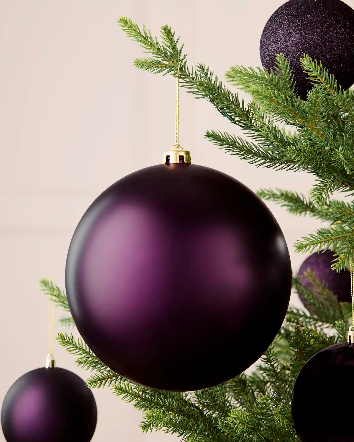 Oversized 20 cm purple matt shatterproof bauble displayed on a Christmas tree with coordinating purple baubles.
