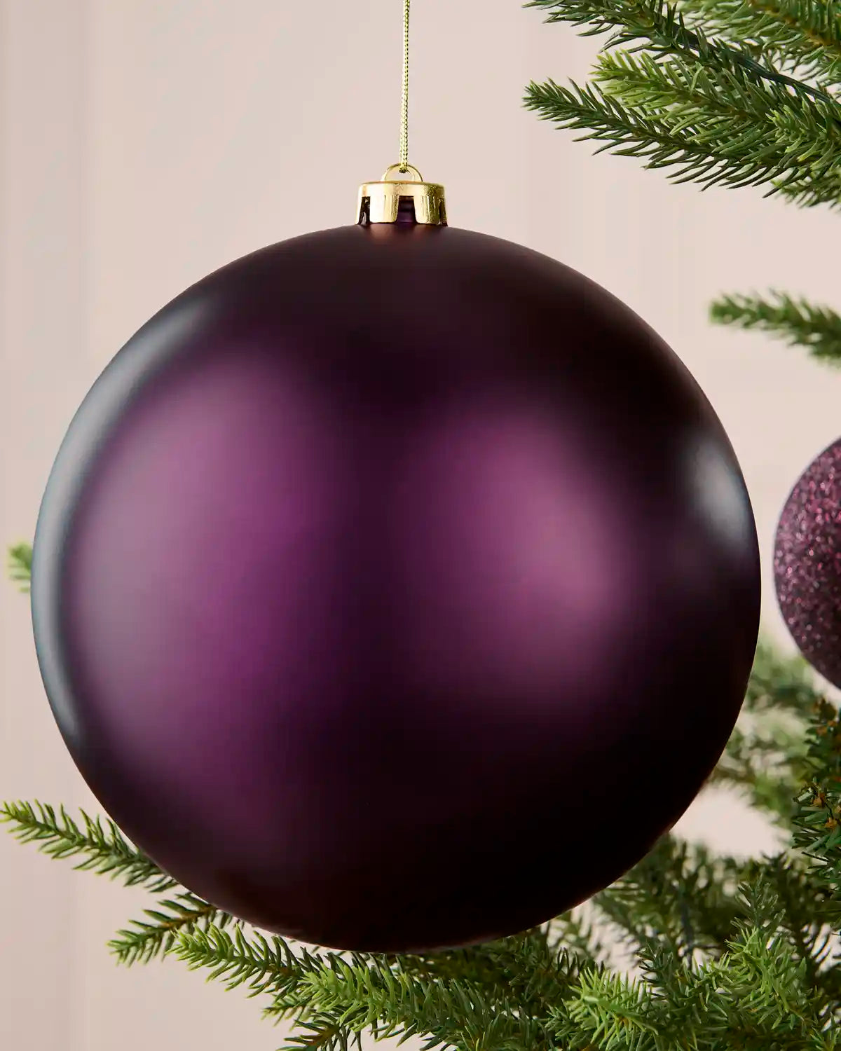 Close-up of a 20 cm oversized purple shatterproof bauble with a smooth matt finish on a Christmas tree.