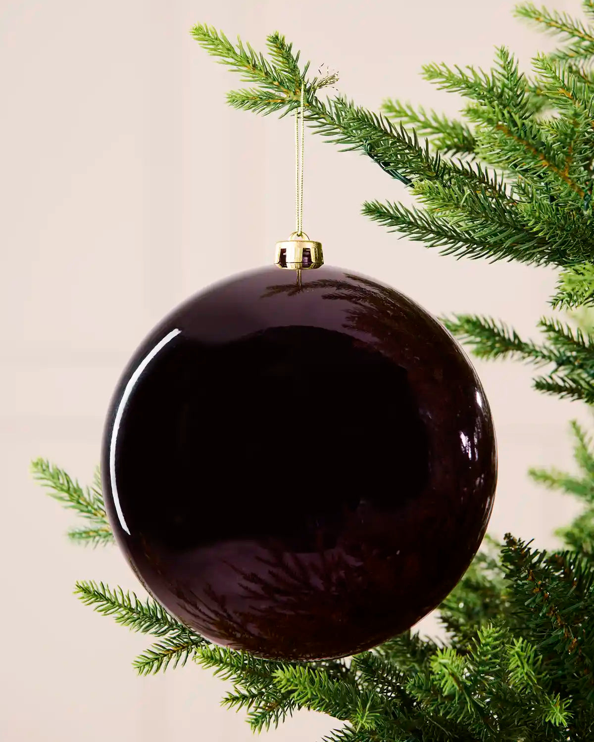 Close-up of a 20 cm oversized purple shatterproof bauble with a shiny finish on a Christmas tree.