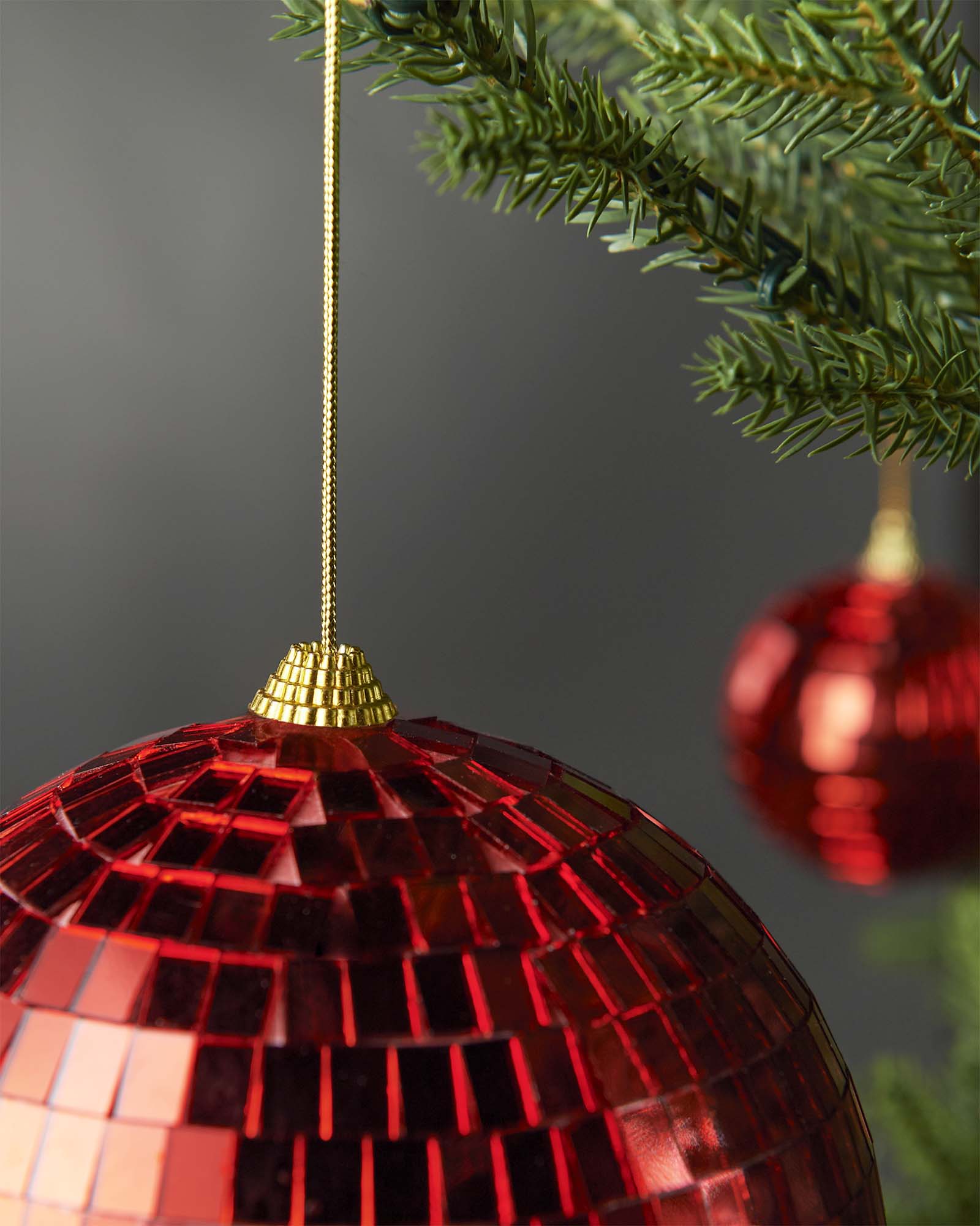 Detailed view of the hanging string and mirrored surface on a red 15cm disco ball bauble.