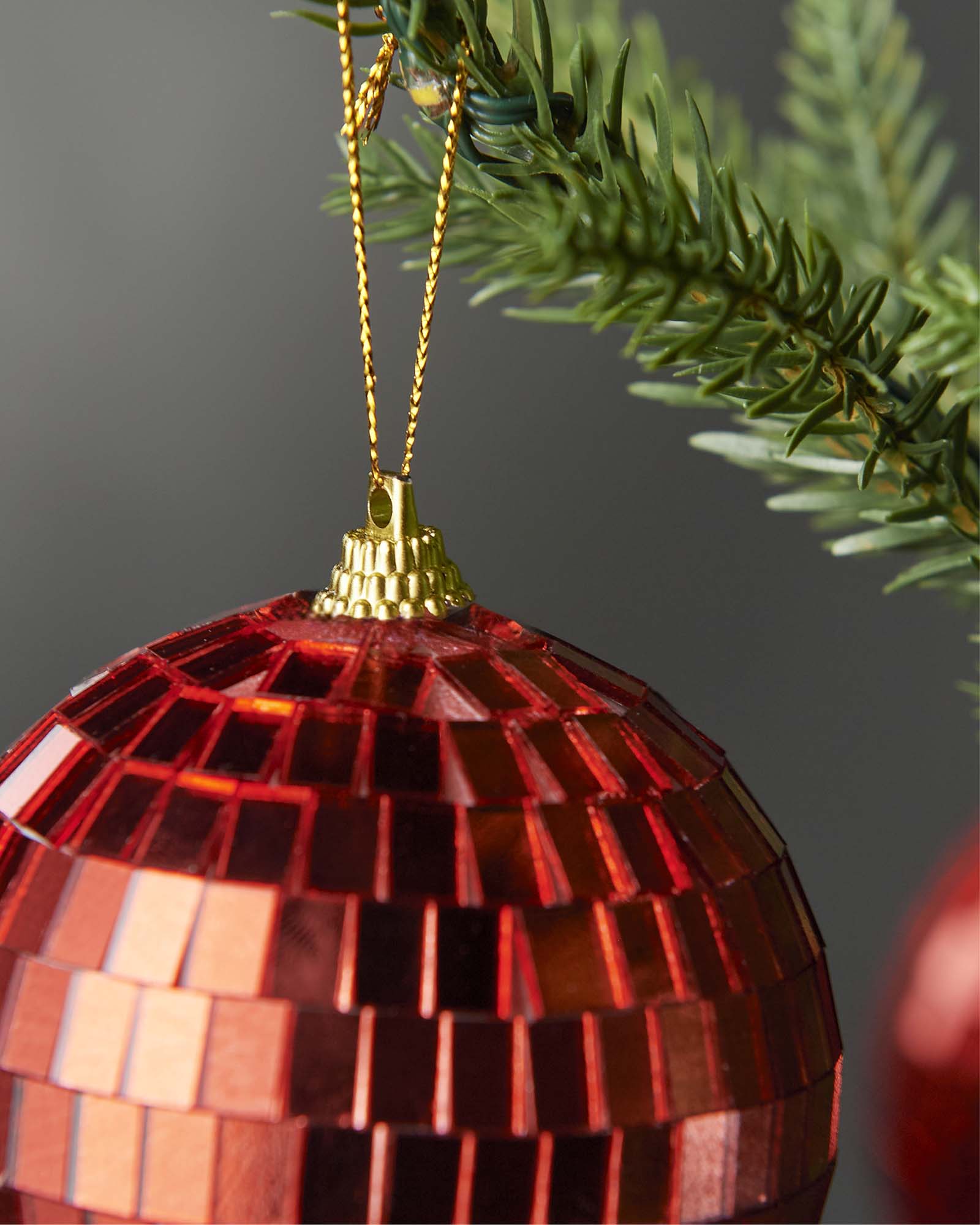 Close-up of the hanging string and top cap on a red 8cm disco ball bauble.