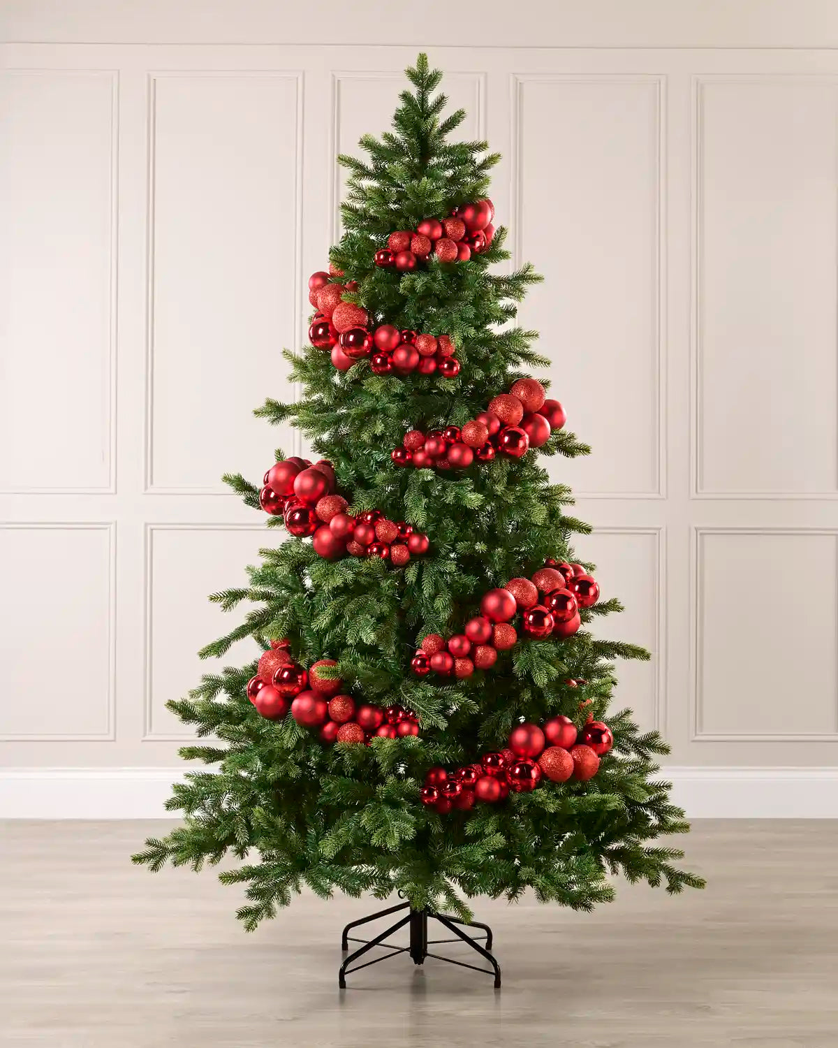 Red bauble cluster arch styled around a green Christmas tree with shiny, matt and glitter baubles.