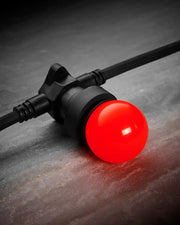 Close-up of a red E27 LED bulb fitted into a black festoon belt on a dark stone-effect surface.