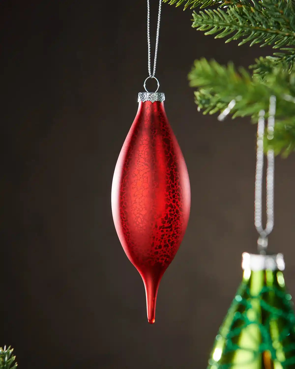 Red glass finial bauble hanging on Christmas tree.