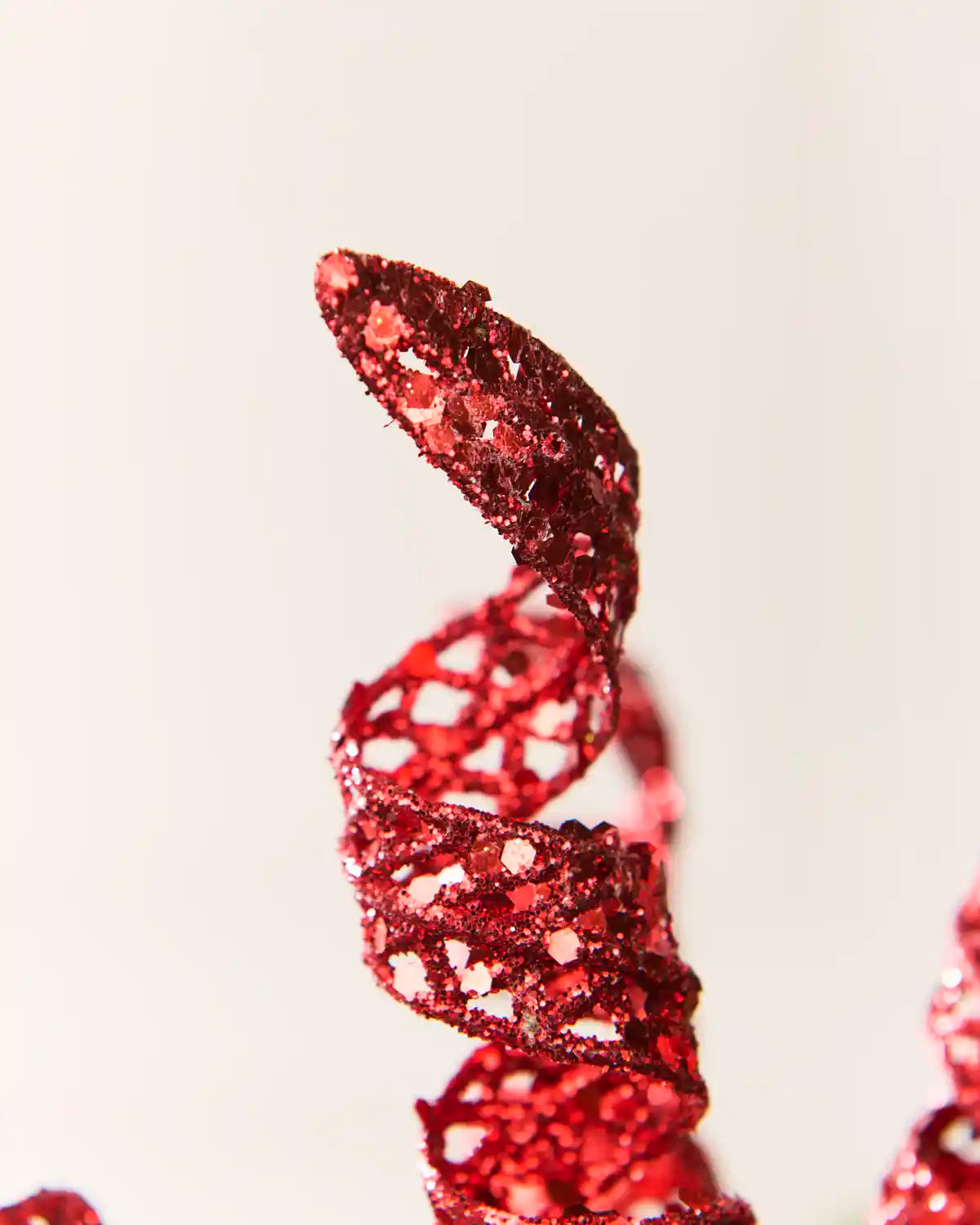 Detailed view of a red glitter spiral pick showing its curled shape and textured reflective finish.
