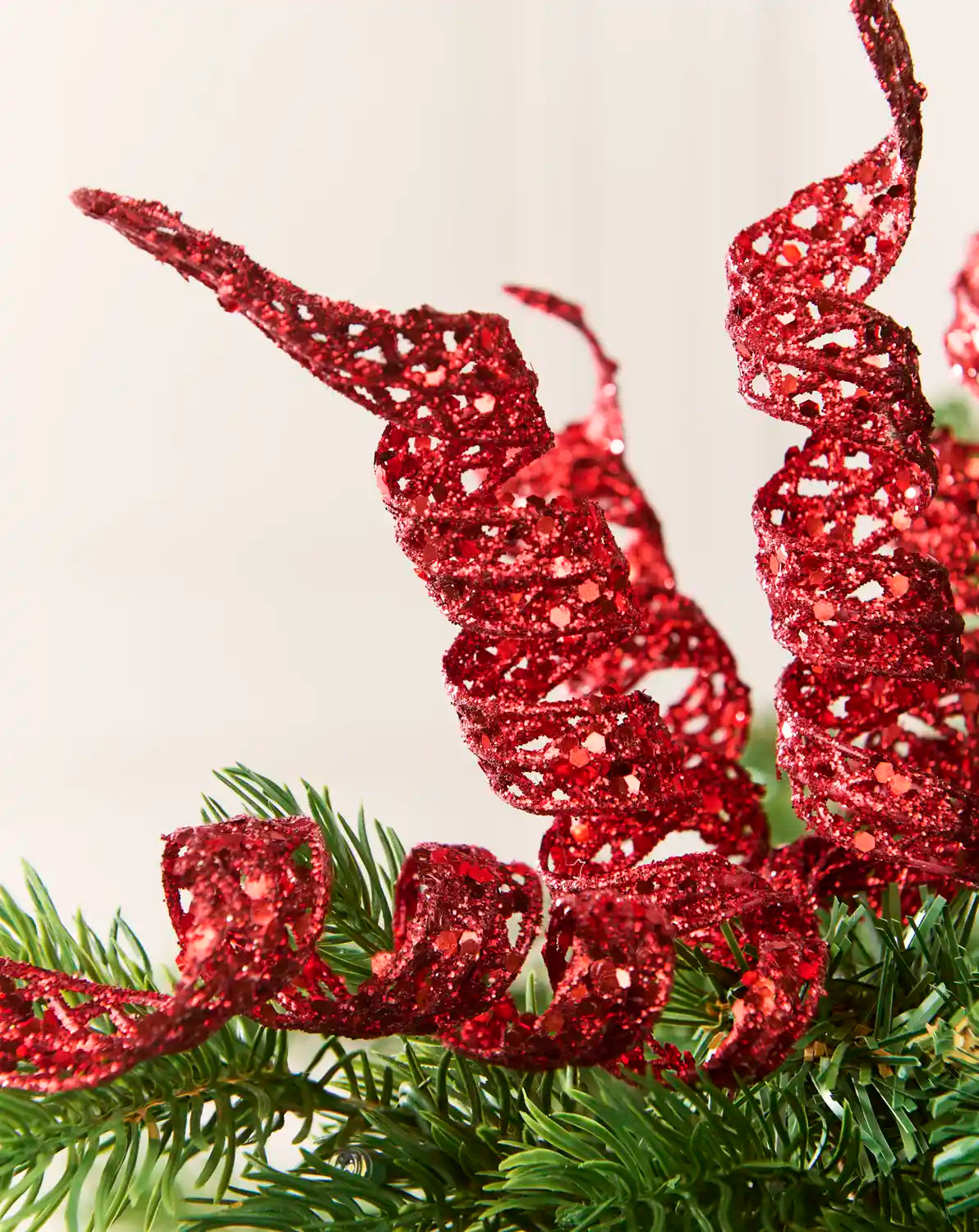 Close-up of red glitter spiral picks showing curled openwork shapes and reflective sequin details.
