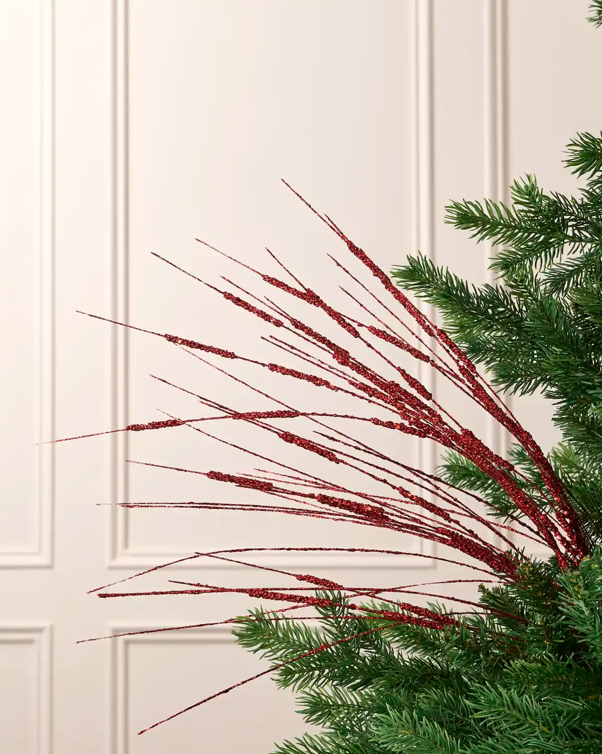 Red 100 cm glitter wispy spray with fine sparkling strands arranged through an artificial Christmas tree.