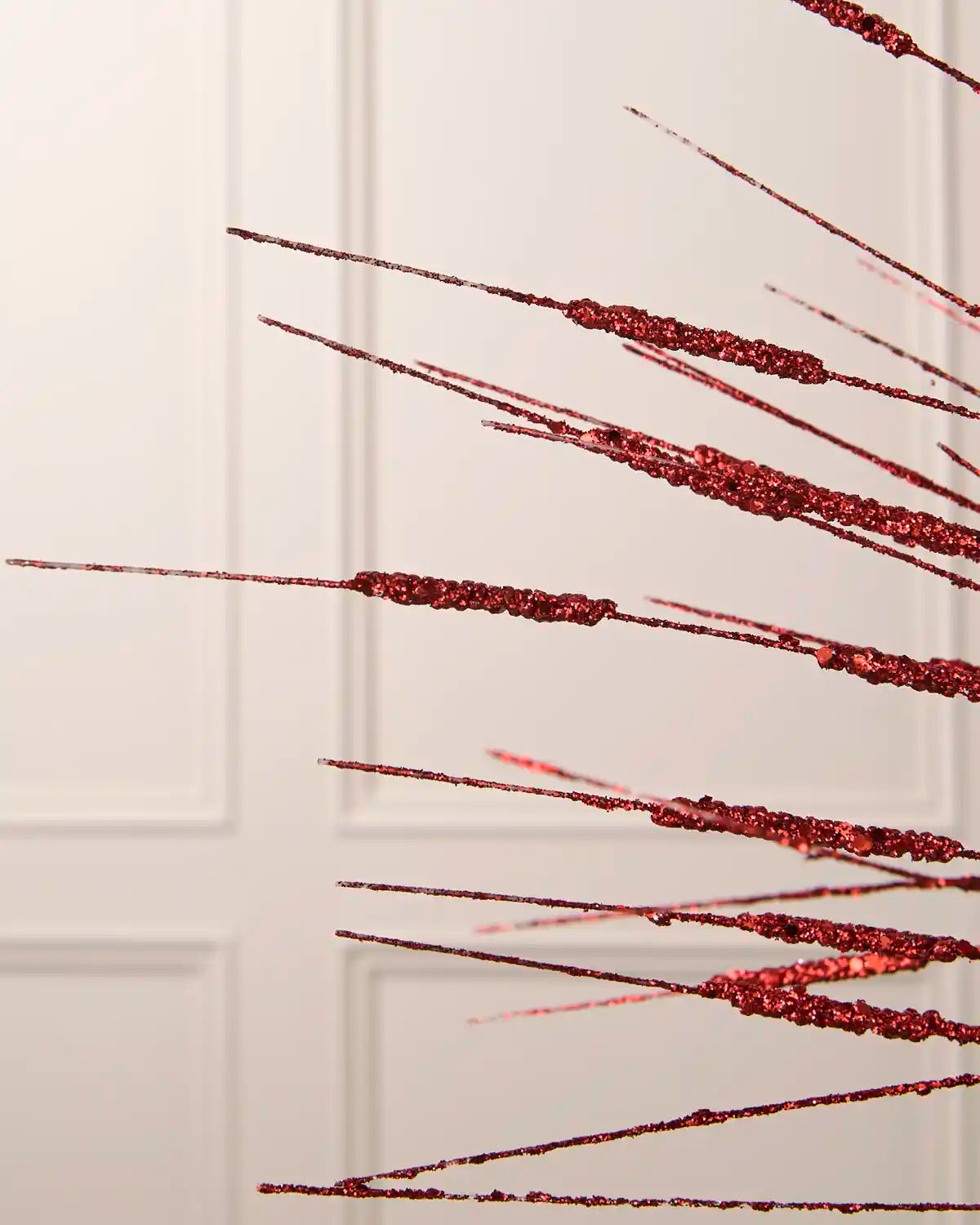 Close-up of the fine red glitter strands on the 100 cm wispy Christmas decoration spray.