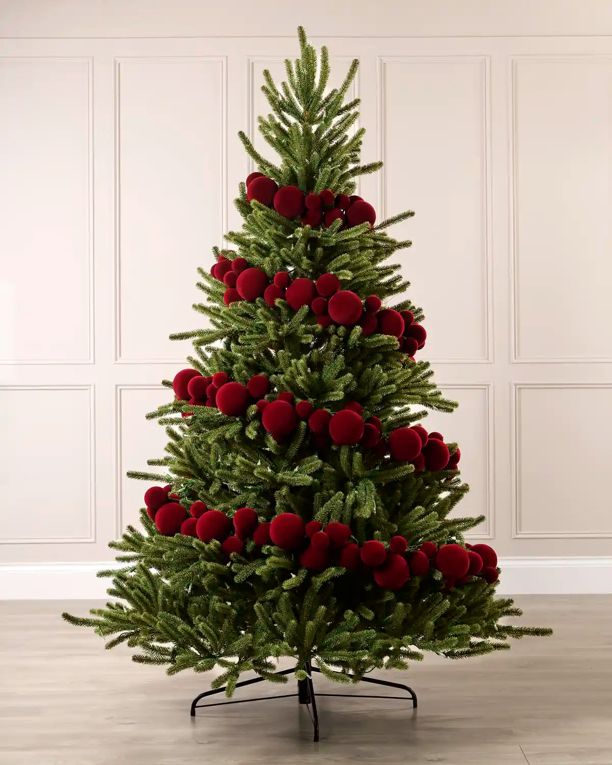 Red velvet bauble garland wrapped around a green Christmas tree with mixed 5cm, 7cm and 10cm baubles.