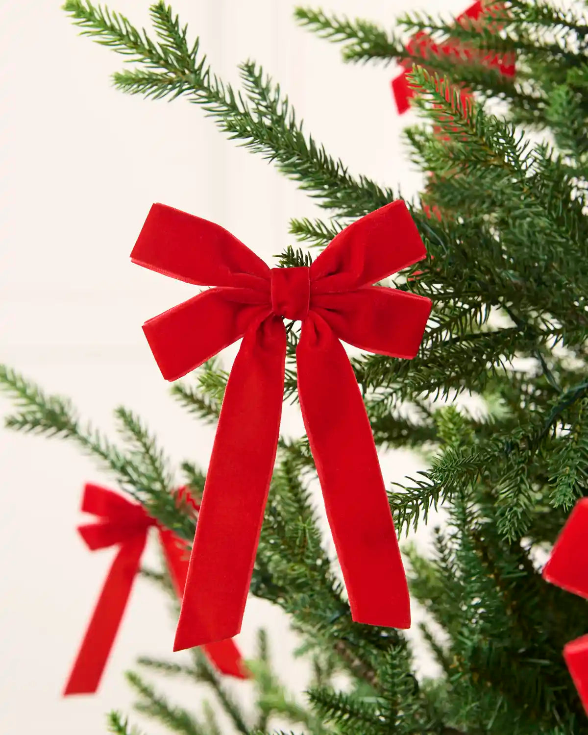Red velvet double bow displayed among multiple matching bows on a Christmas tree.