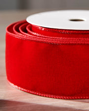 Close-up of red velvet ribbon on a roll, showing the soft texture and wired edge.
