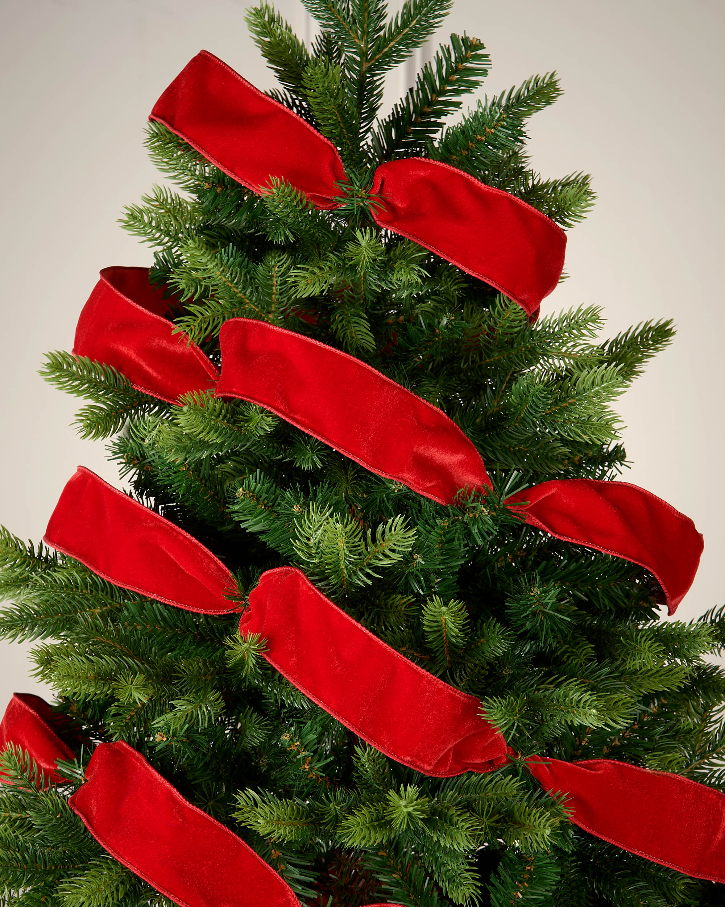 Red velvet ribbon wrapped around a Christmas tree as a festive decoration.