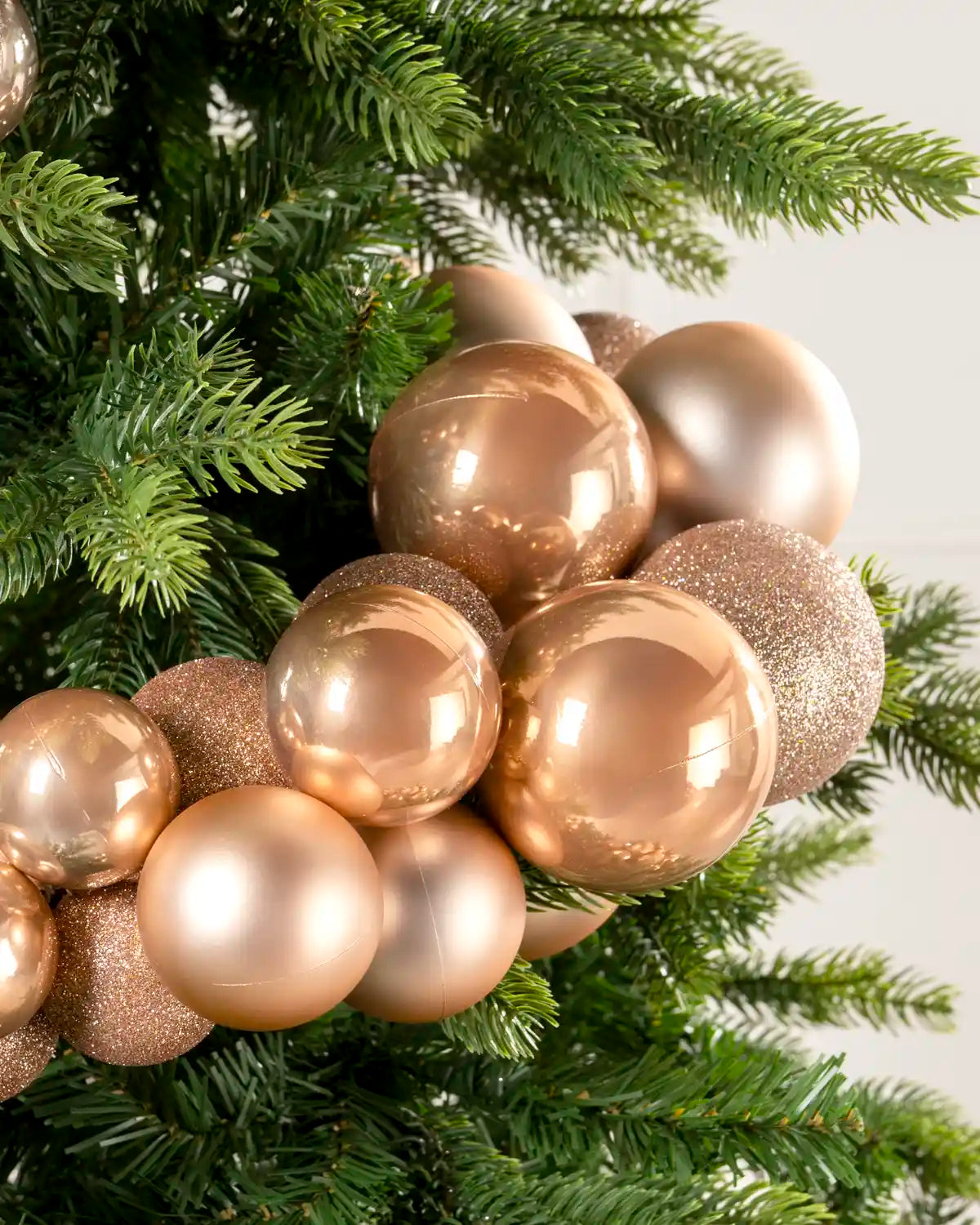 Close-up of rose gold baubles showing shiny, matt and glitter finishes on a Christmas tree.