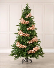 Rose gold bauble cluster arch styled around a green Christmas tree with shiny, matt and glitter baubles.