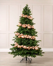 Rose gold bauble garland wrapped around a green Christmas tree with shiny, matt and glitter baubles.