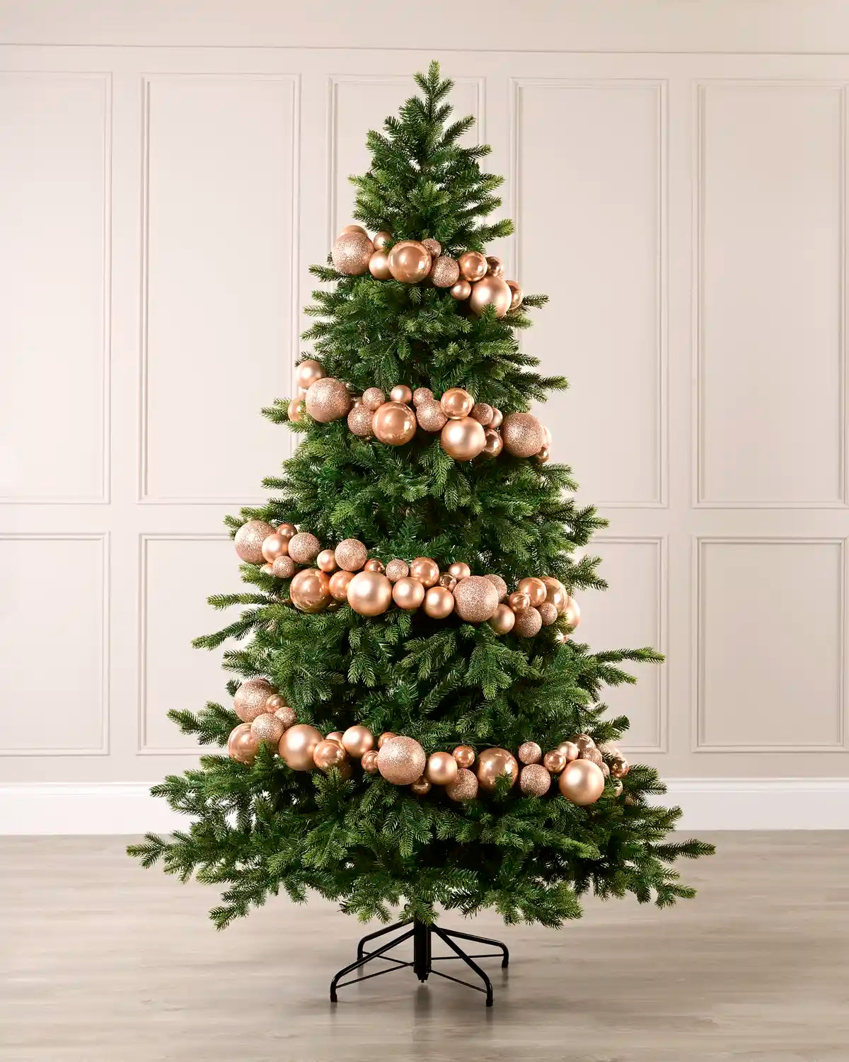 Rose gold bauble garland wrapped around a green Christmas tree with shiny, matt and glitter baubles.