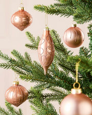 Mixed rose gold glass baubles with matt, shiny and glitter finishes on a Christmas tree.