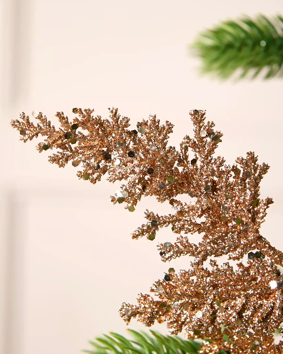 Close-up of the tip of a rose gold glitter leaf pick with a sparkling textured finish.