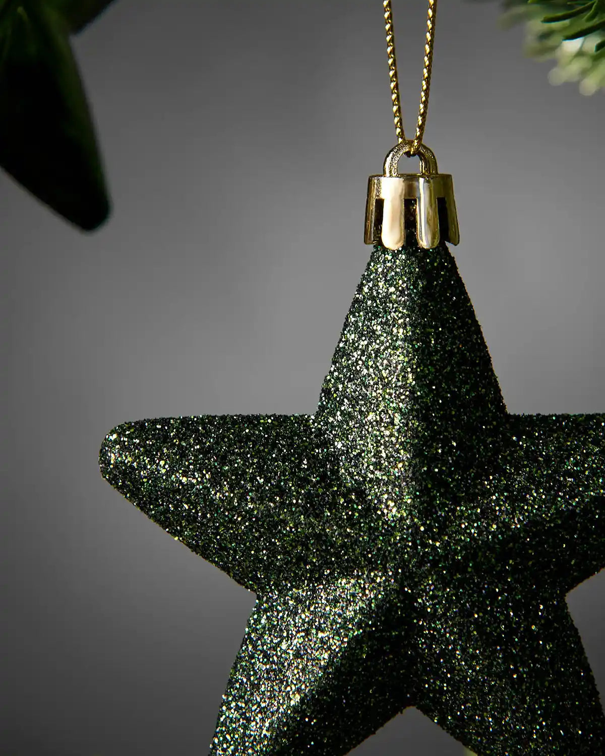 Detailed close-up of a sage green 7cm glitter hanging star showing the textured finish and gold cap.