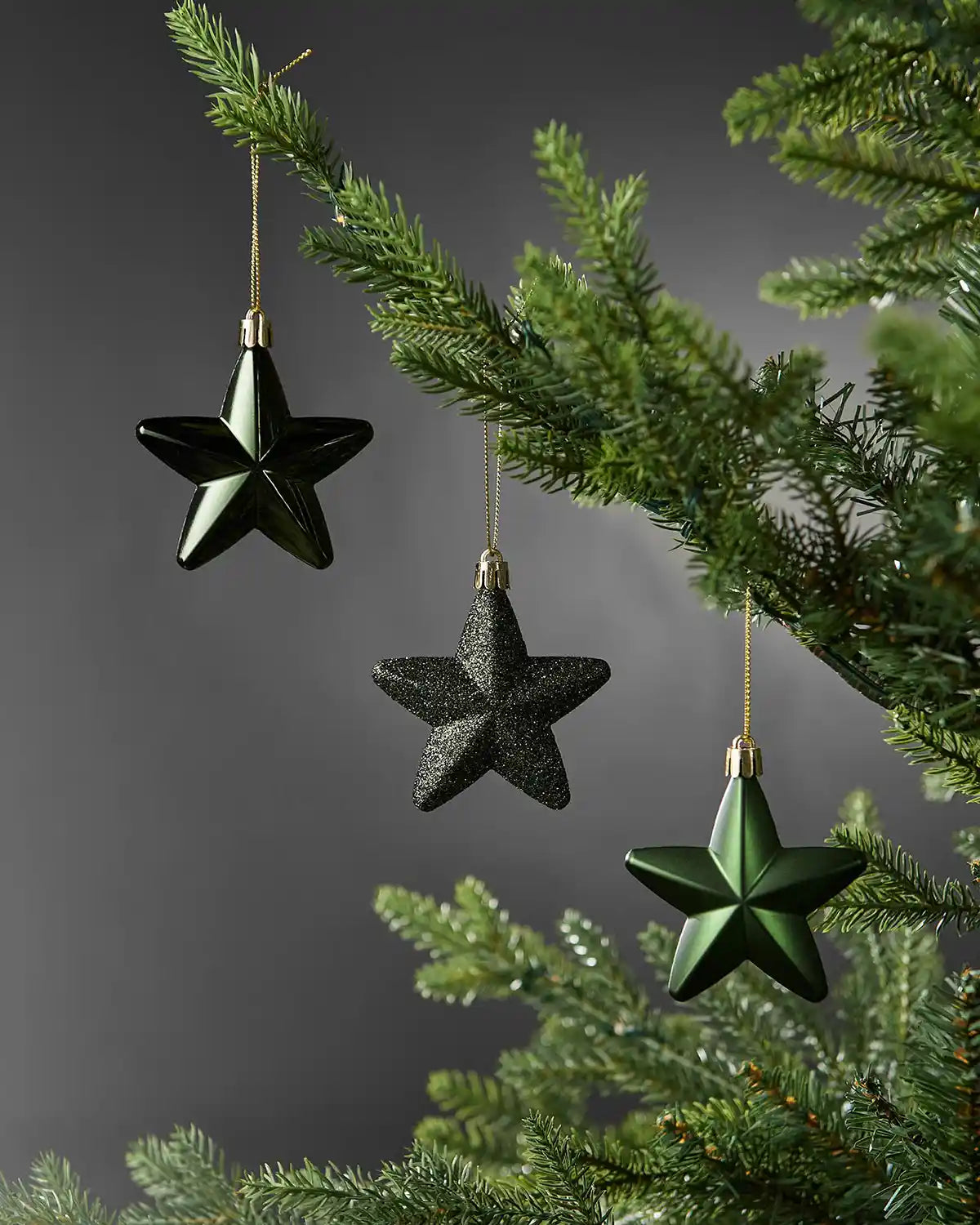 Sage green 7cm hanging star decorations in shiny, glitter and matte finishes displayed on a Christmas tree.