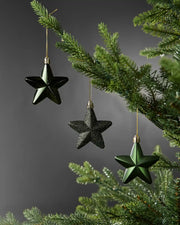 Sage green 7cm hanging star decorations in shiny, glitter and matte finishes displayed on a Christmas tree.