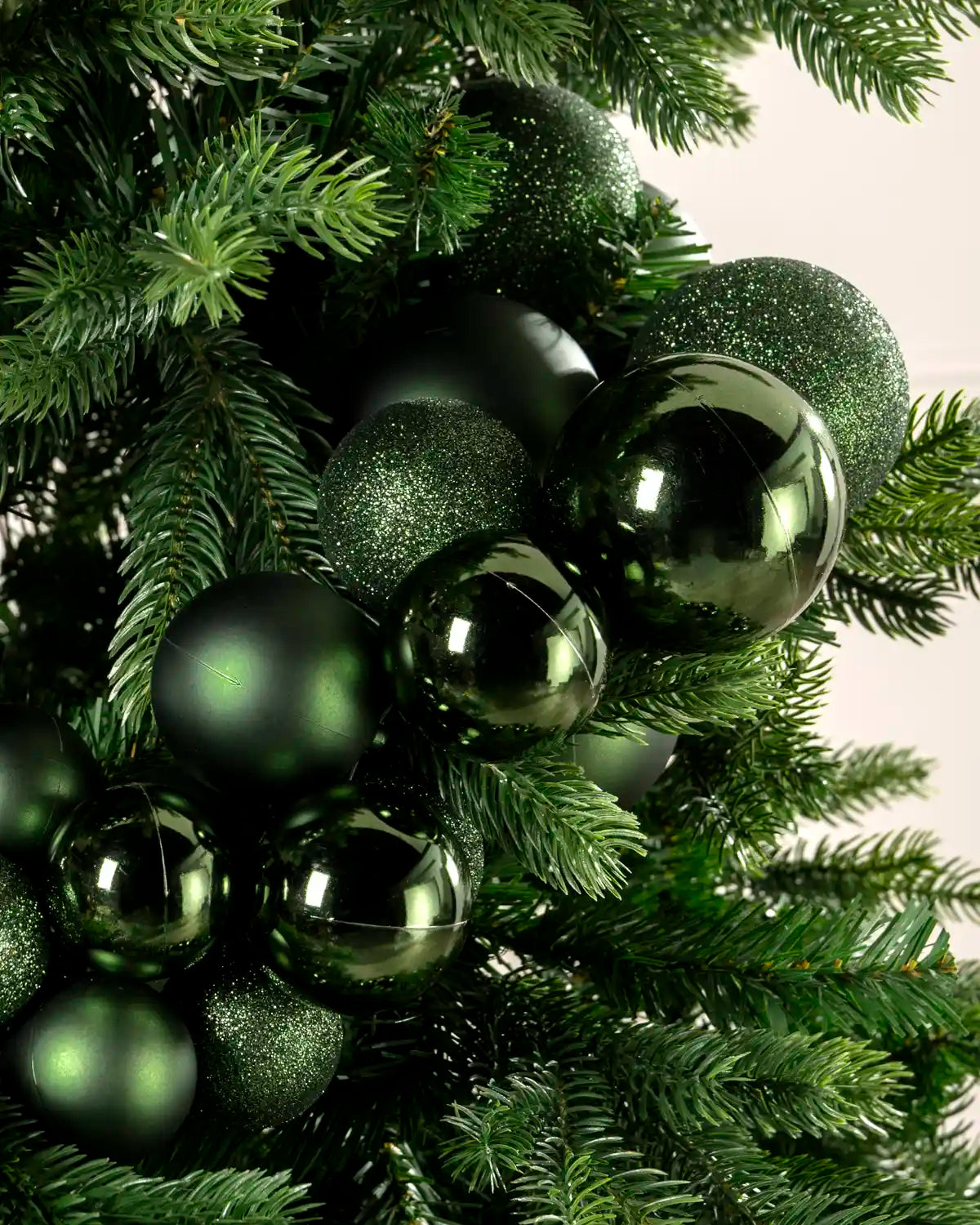 Close-up of sage green baubles showing shiny, matt and glitter finishes on a Christmas tree.