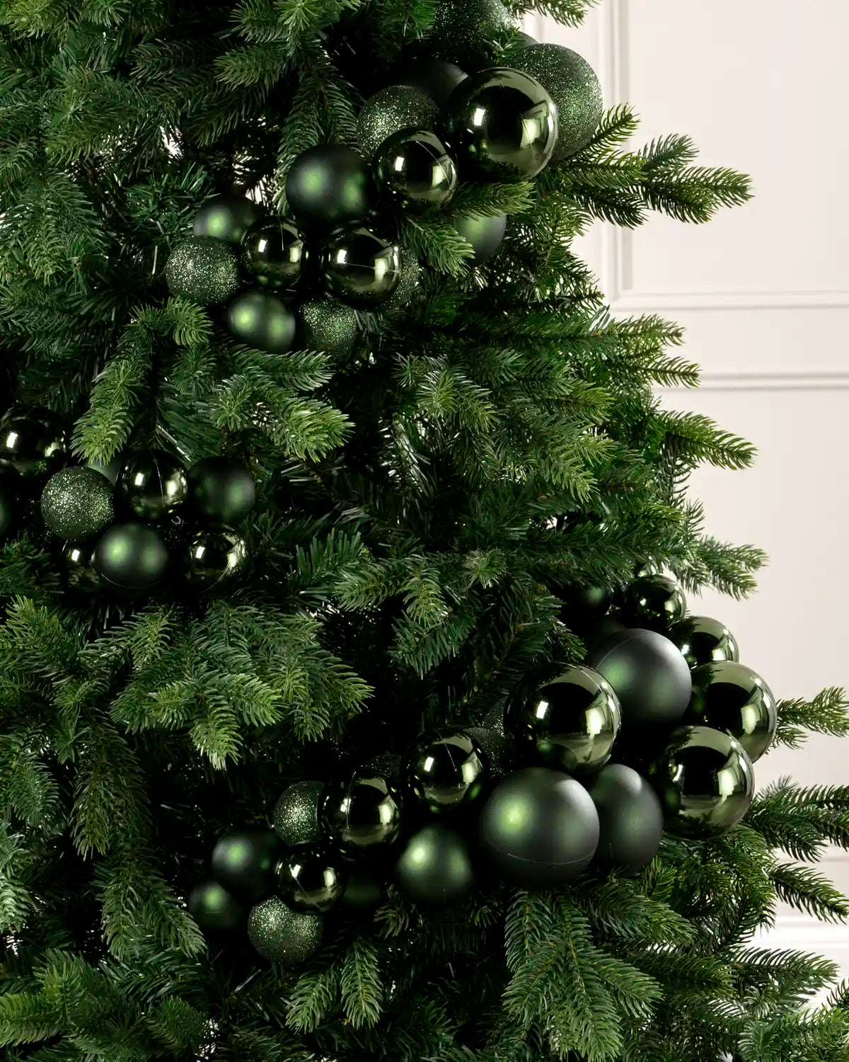 Close-up of sage green bauble cluster arch on a Christmas tree showing mixed sizes and finishes.