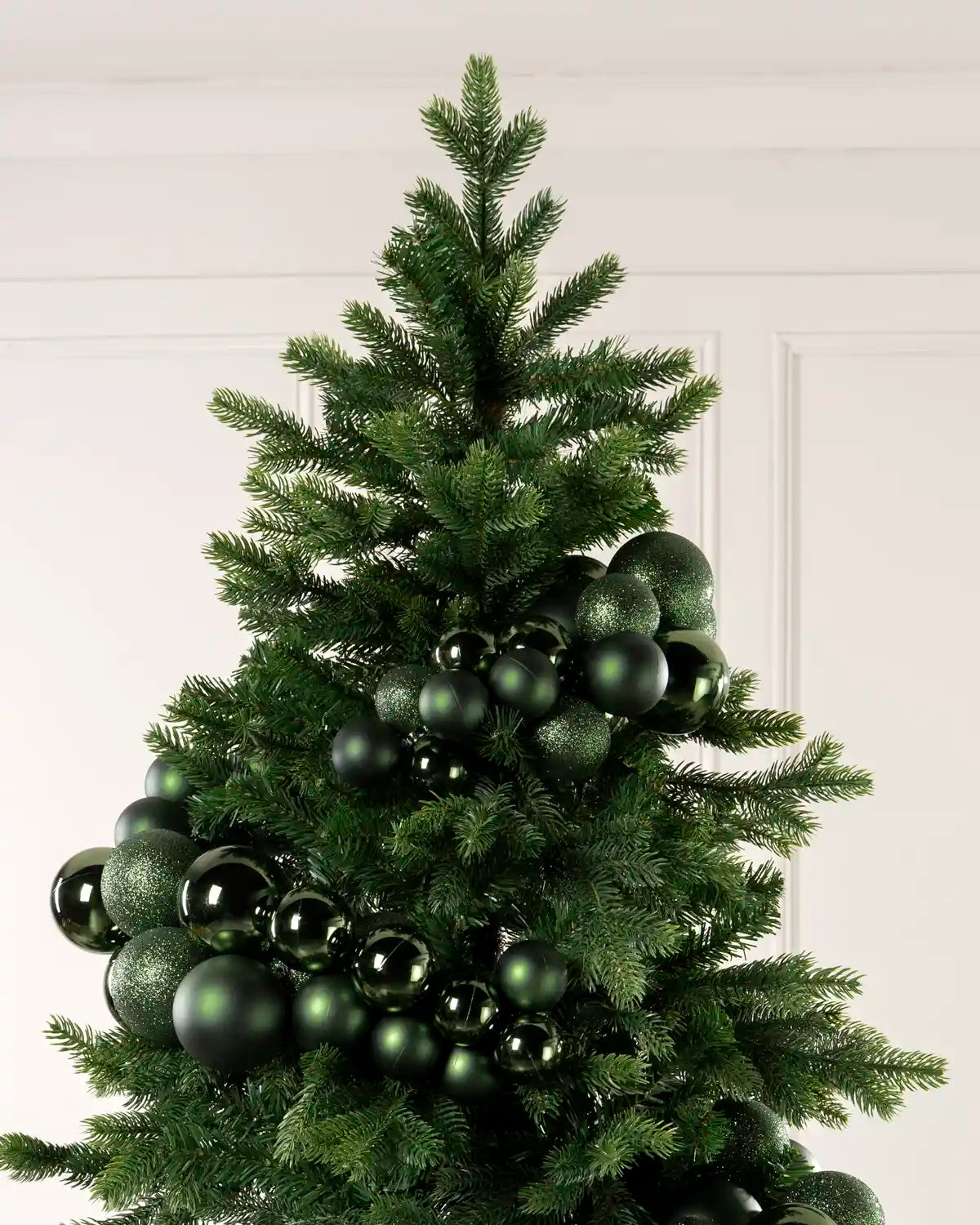 Sage green bauble cluster arch arranged through the upper branches of a green Christmas tree.