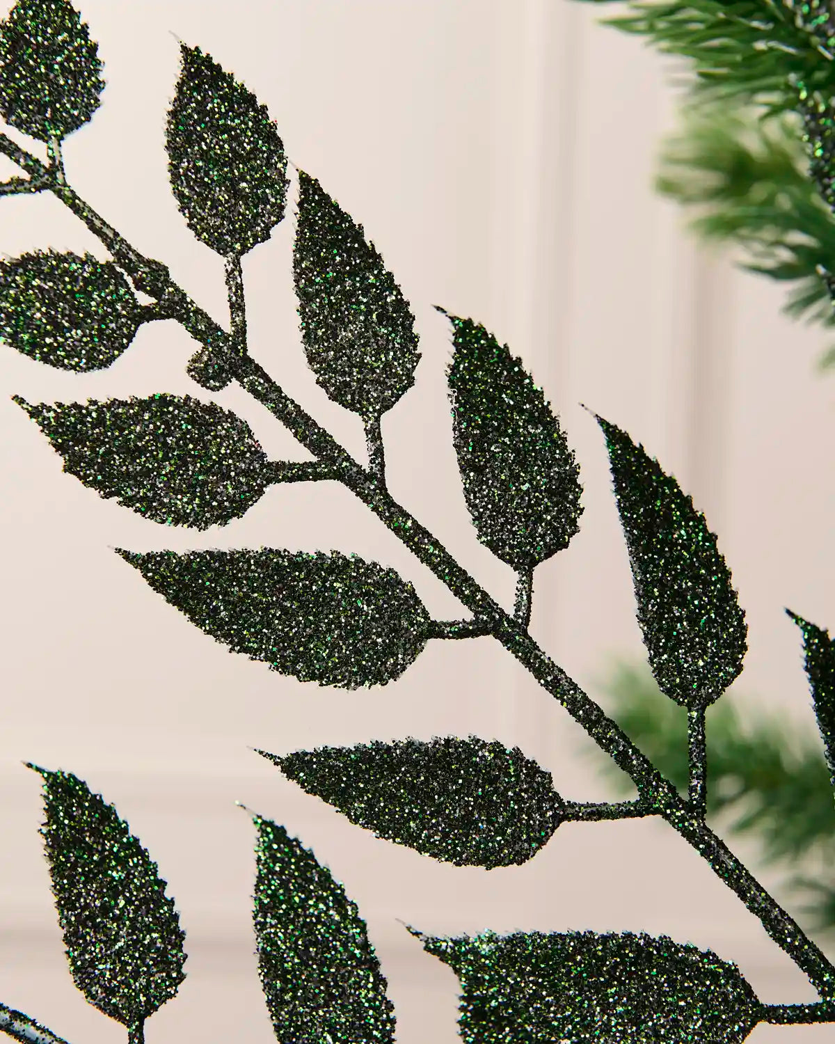Close-up of the glitter-coated sage green leaves and branching stem on the Christmas tree spray.