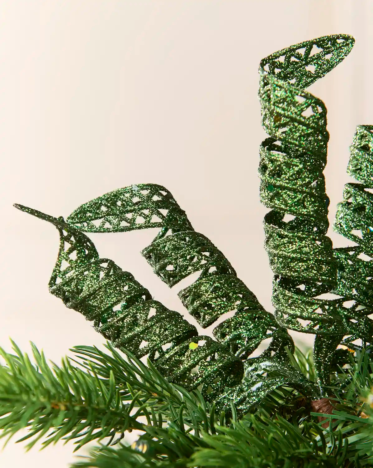 Close-up of sage green glitter spiral picks showing curled openwork shapes and reflective sequin details.