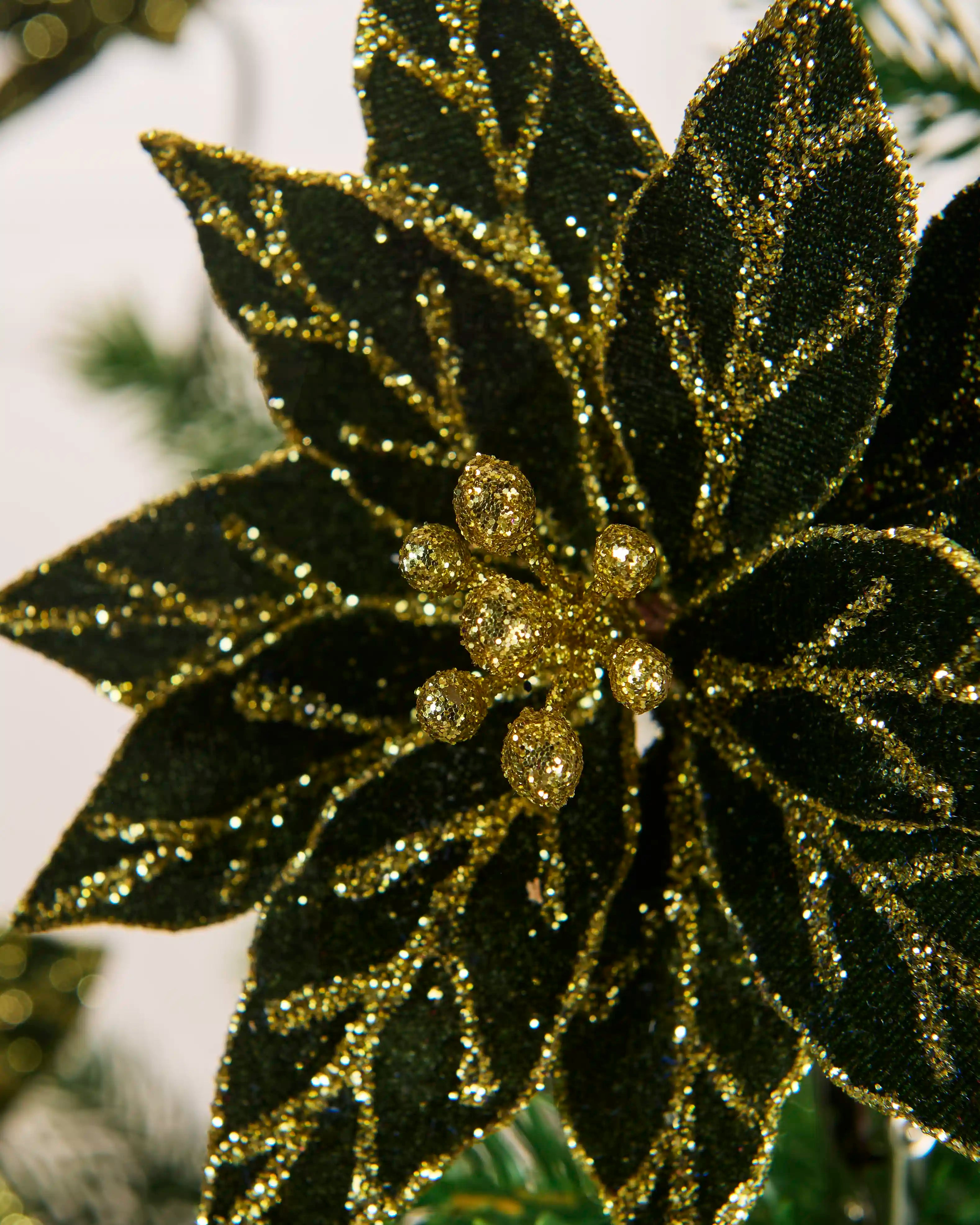 Close-up of the glittered centre and layered sage green leaves of the 15 cm artificial poinsettia.