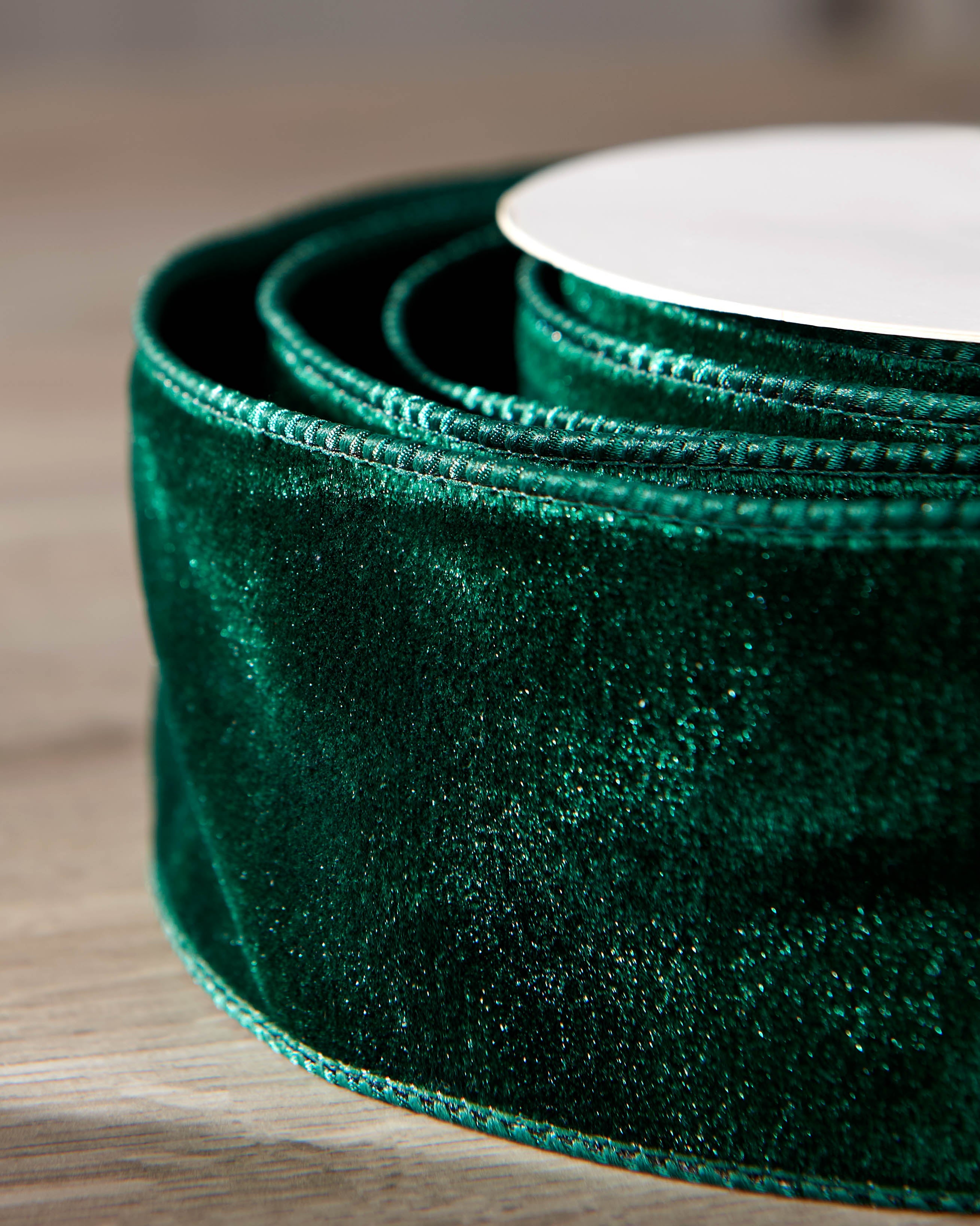 Close-up of sage green velvet ribbon on a roll, showing the soft texture and wired edge.