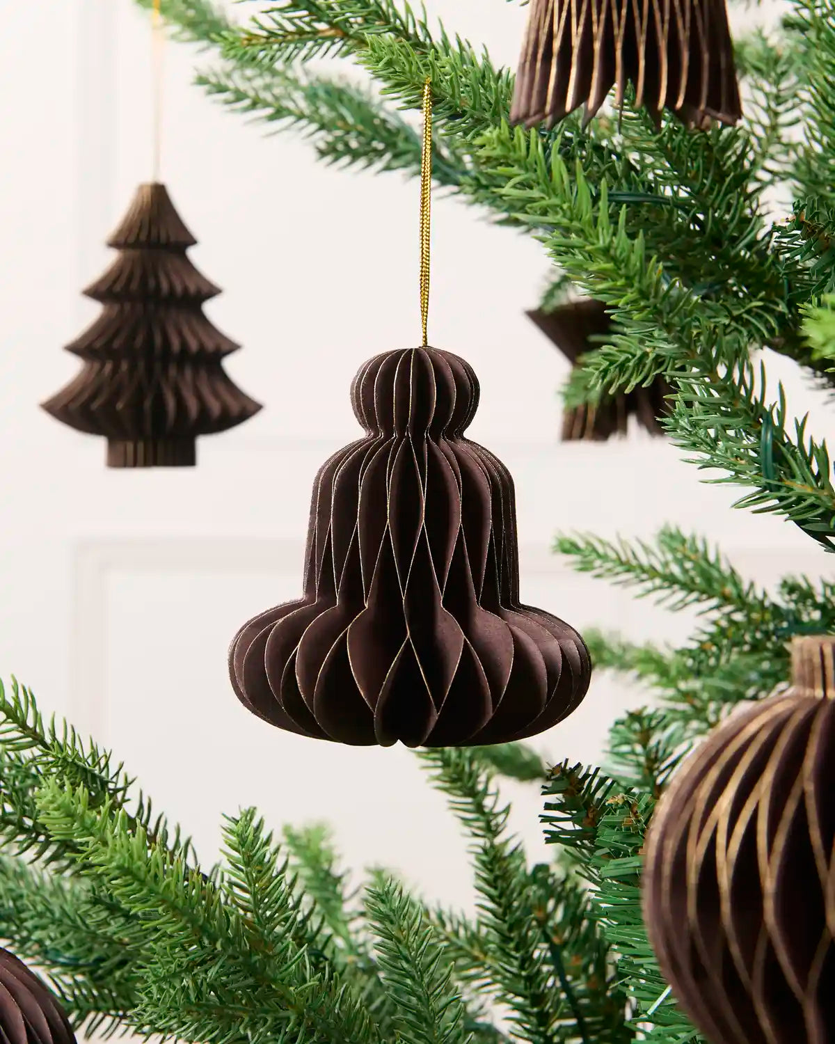 Close-up of an espresso folded paper bell decoration hanging from a Christmas tree.