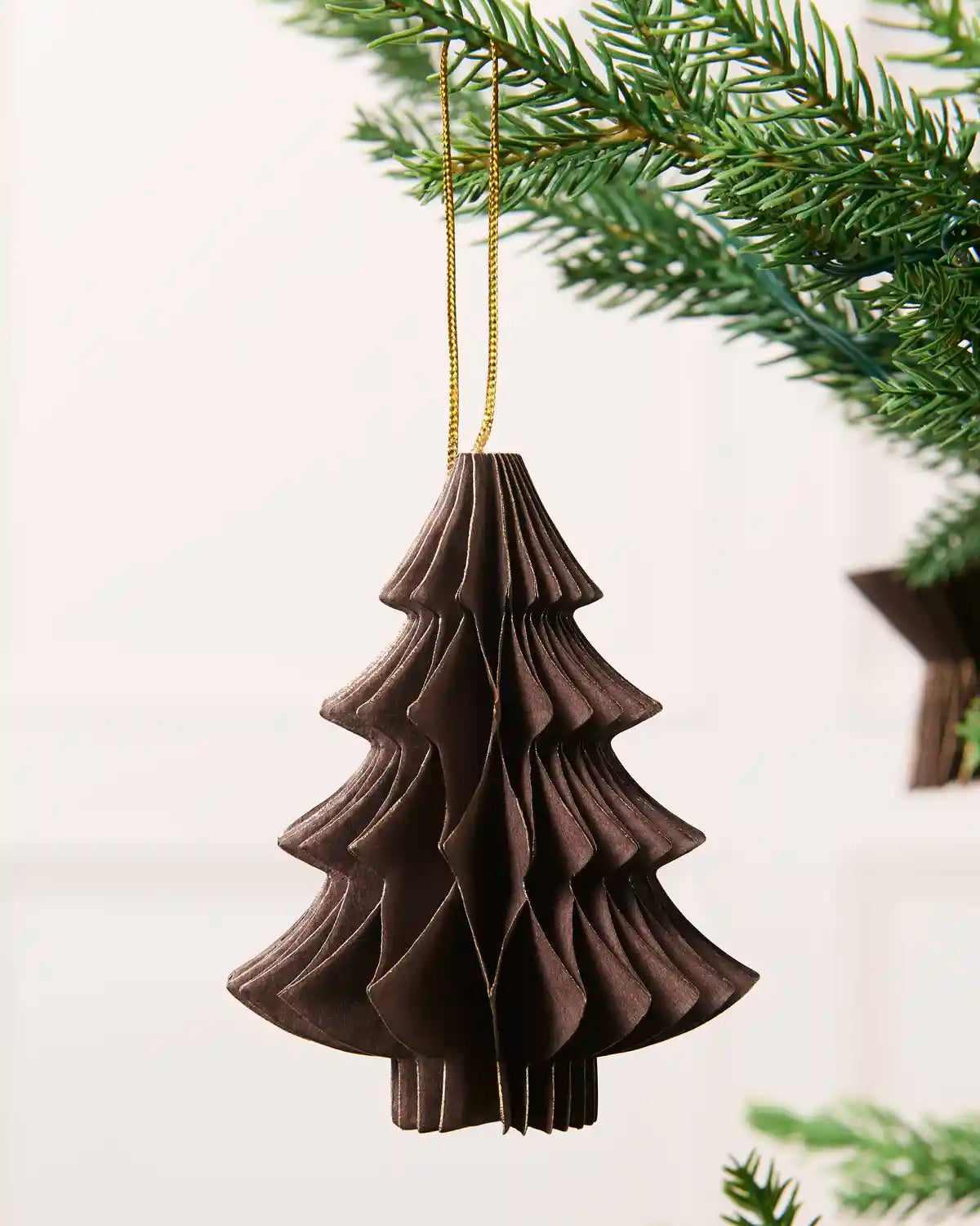 Close-up of an espresso folded paper Christmas tree decoration with gold glitter edging.