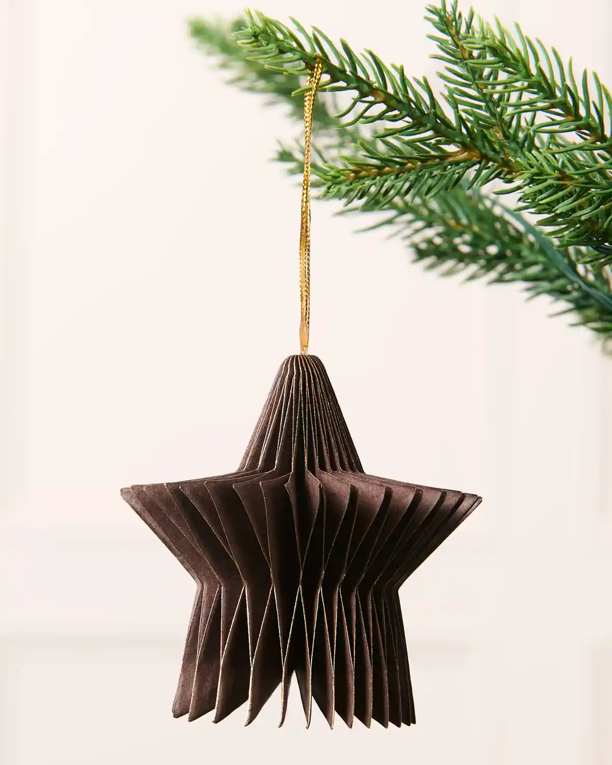 Close-up of an espresso folded paper star decoration hanging from a Christmas tree.