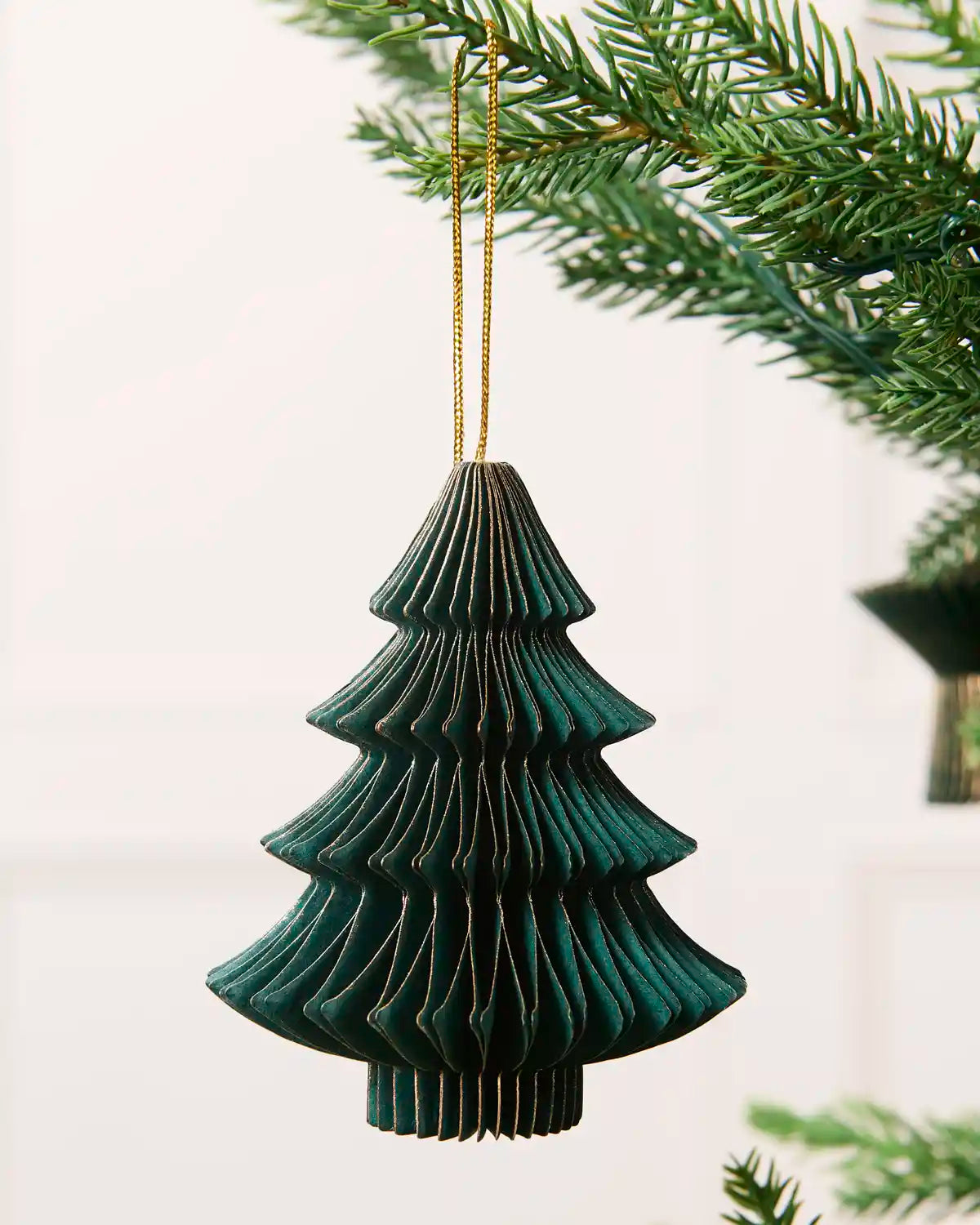 Close-up of a sage green folded paper Christmas tree decoration with gold glitter edging.