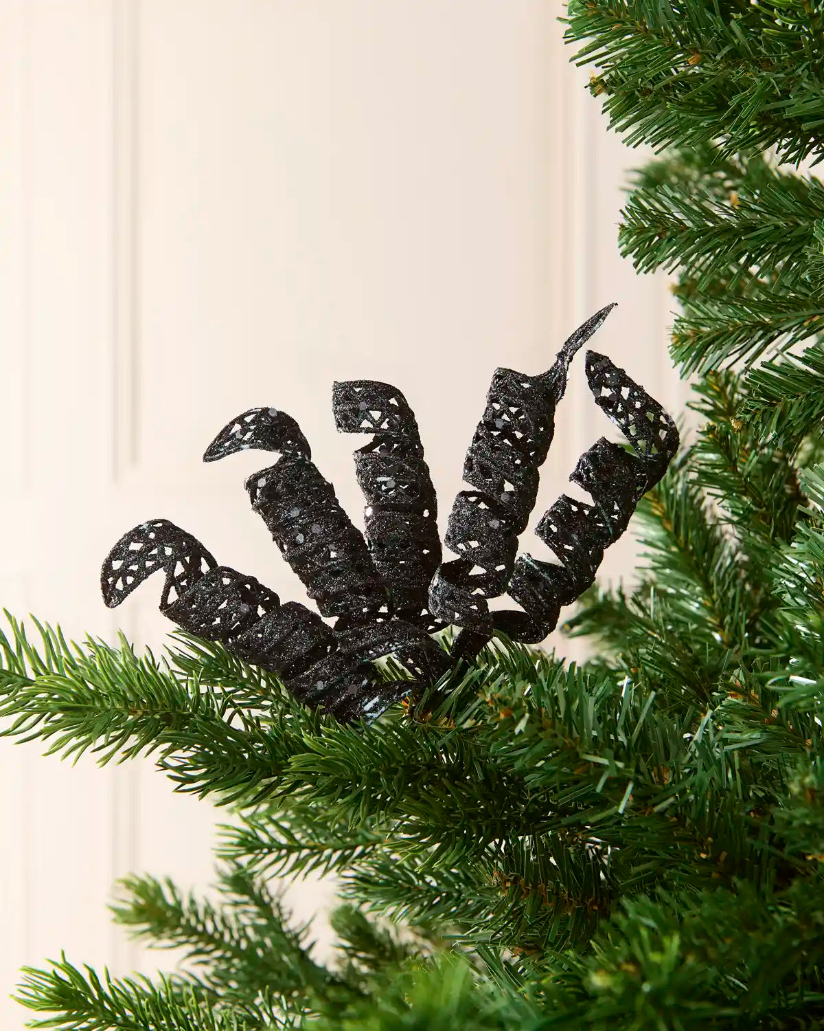 Set of three 18 cm black glitter spiral picks arranged among green Christmas tree branches.
