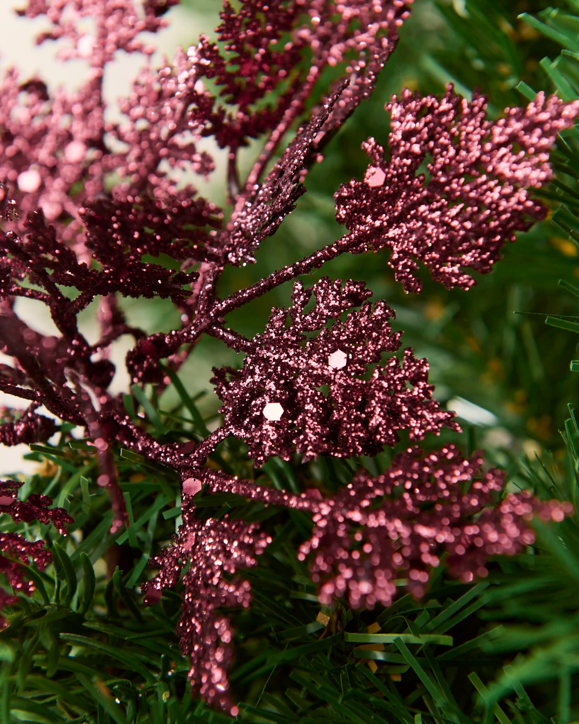 Detailed close-up of burgundy glitter leaf picks with textured foliage and reflective glitter pieces.