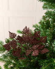 Espresso 19 cm glitter leaf picks arranged among the branches of a Christmas tree.