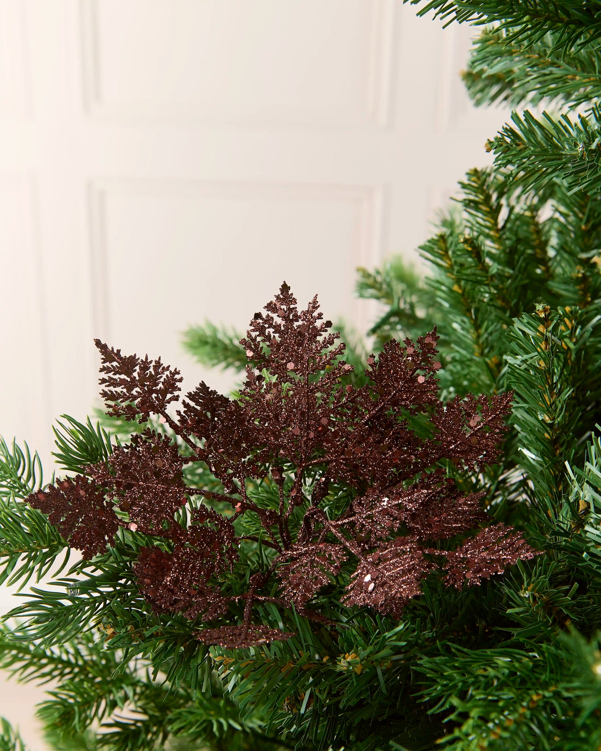Espresso 19 cm glitter leaf picks arranged among the branches of a Christmas tree.