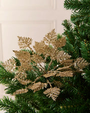 Set of three 19 cm gold glitter leaf picks arranged among green Christmas tree branches.