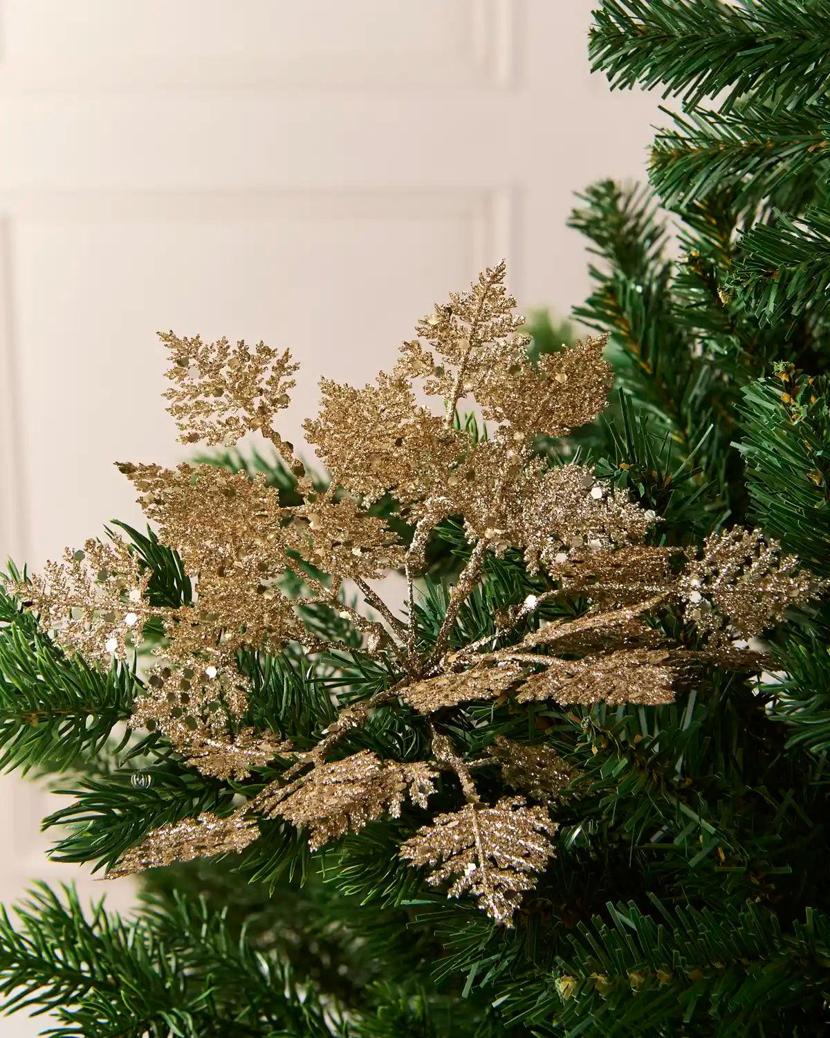 Set of three 19 cm gold glitter leaf picks arranged among green Christmas tree branches.