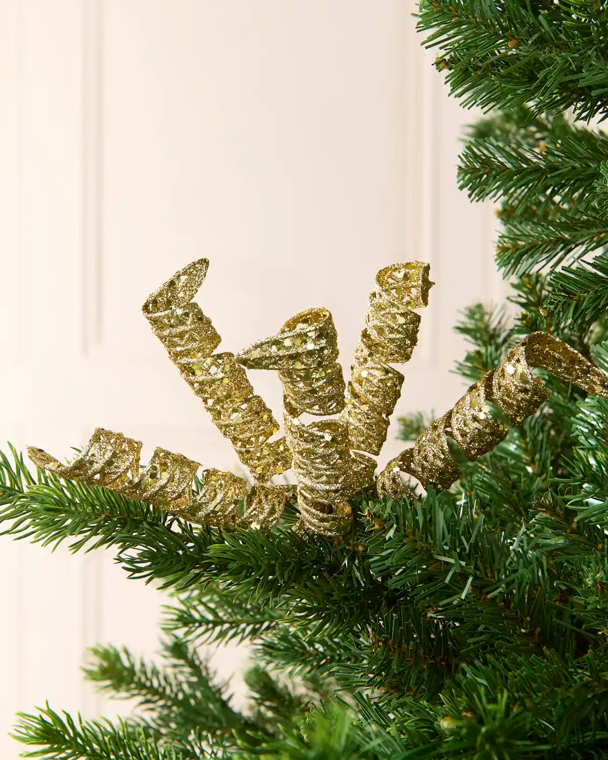 Set of three 18 cm gold glitter spiral picks arranged among green Christmas tree branches.
