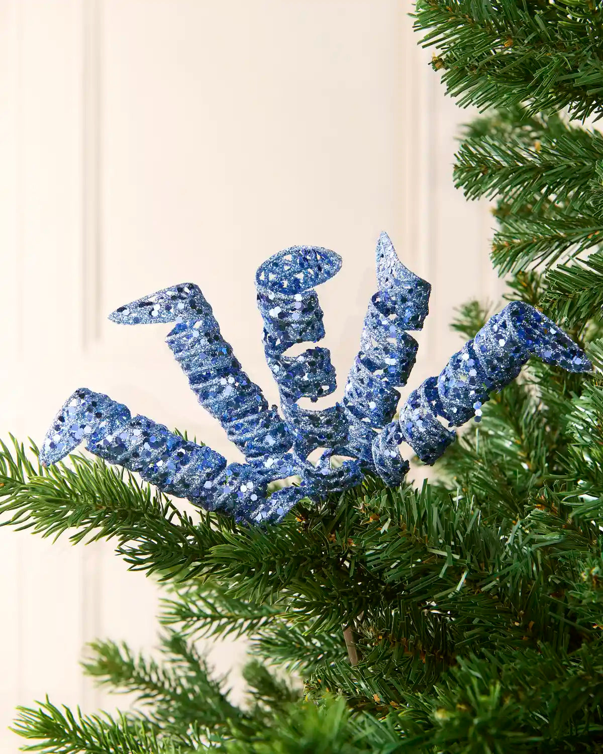 Set of three 18 cm ice blue glitter spiral picks arranged among green Christmas tree branches.