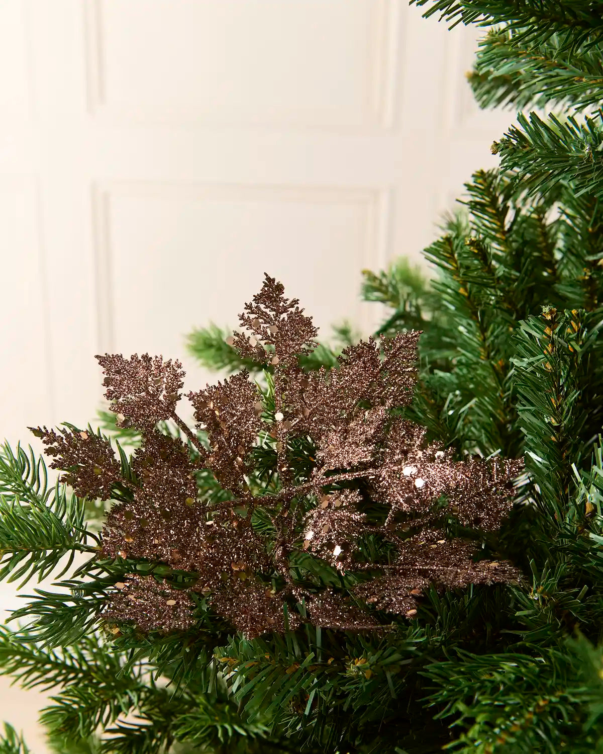 Set of three 19 cm mocha glitter leaf picks arranged among green Christmas tree branches.